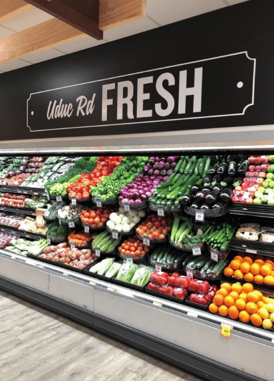 Commercial produce refrigeration display case keeping fresh fruits and vegetables properly cooled in a grocery store.
